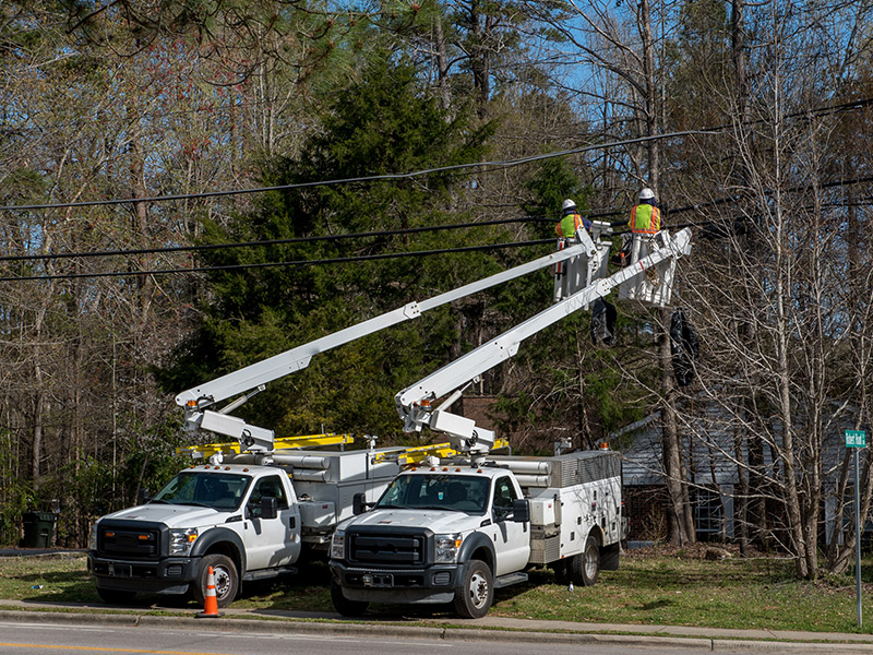 Line workers servicing overhead utility lines from bucket trucks.