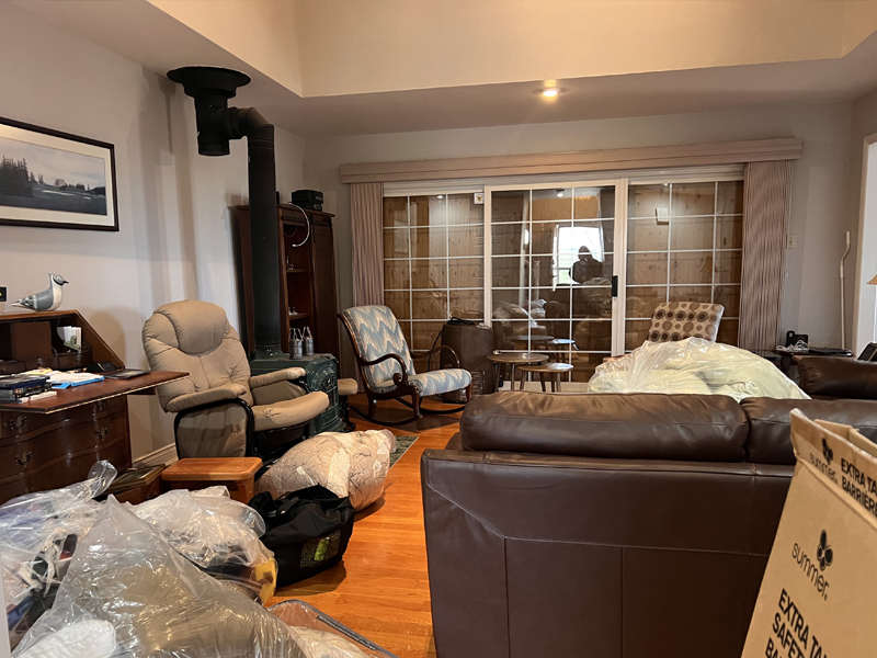 Living room before decluttering and home transition support, with packed items, bags, and furniture gathered in the space.
